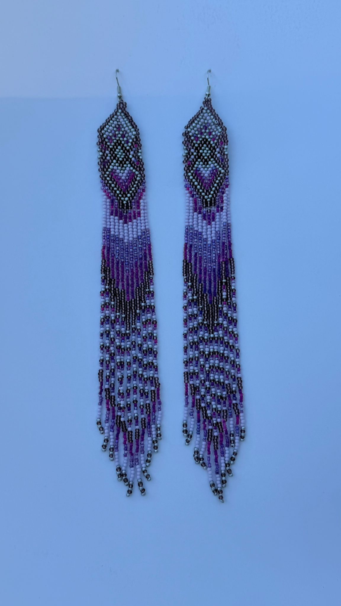 Pair of long beaded earrings in purple, black, and silver with geometric tops and fringe strands.