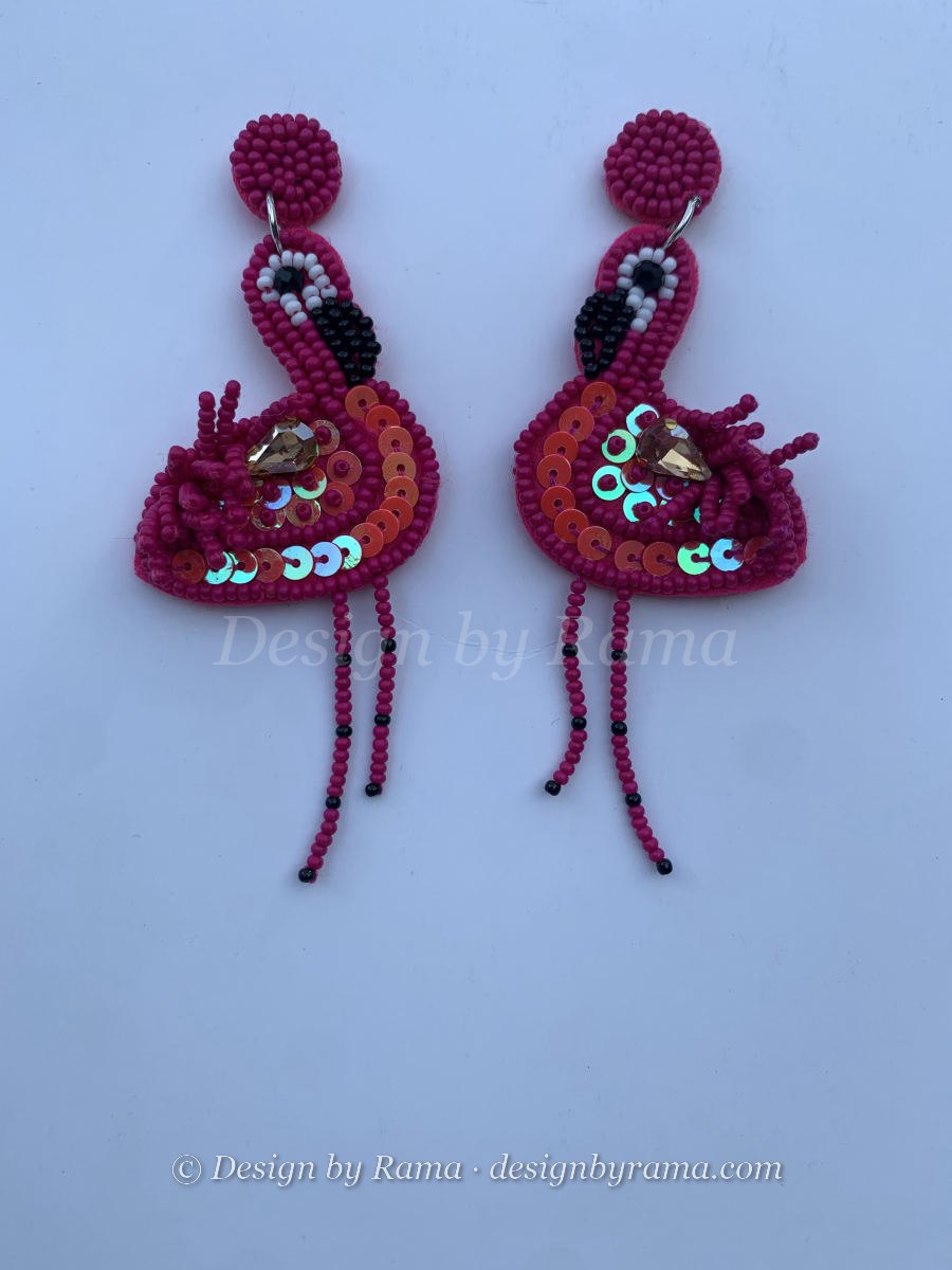 Beaded magenta flamingo earrings with sequin-covered iridescent wings, amber crystal body accent, dangling black bead legs, and round stud top.